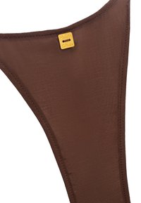 Slip di bikini marrone con una texture liscia, caratterizzato da un'etichetta dorata impresso con "Manila Grace". Motivo: solid, con design minimalista.