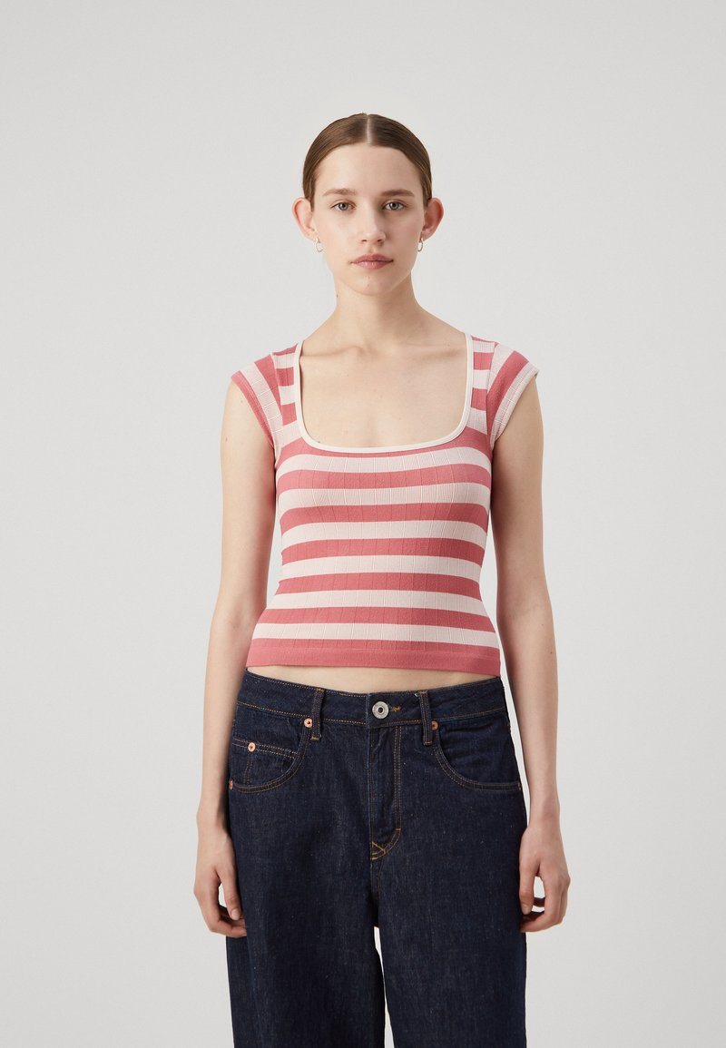 Haut crop rayé en rose clair et rose foncé avec un décolleté carré et une coupe ajustée. Porté avec un jean en denim foncé taille haute.