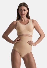Naadloze nude bh en hoog-gehoge slipset gemaakt van zachte, rekbare stof, met een rond decolleté en een ondersteunend ontwerp.