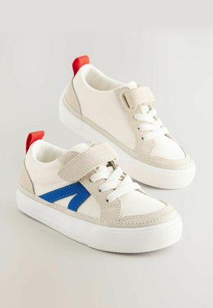 Balti ir kreminiai sportbačiai su mėlynais akcentais, turintys Velcro dirželį ir raudoną kulno juostą. Tvirtas gumos padas su baltais raišteliais.