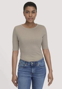 Beige T-shirt met korte mouwen en een ronde halslijn, aansluitend design, zachte textuur, gecombineerd met blauwe high-waisted jeans met traditionele zakken.
