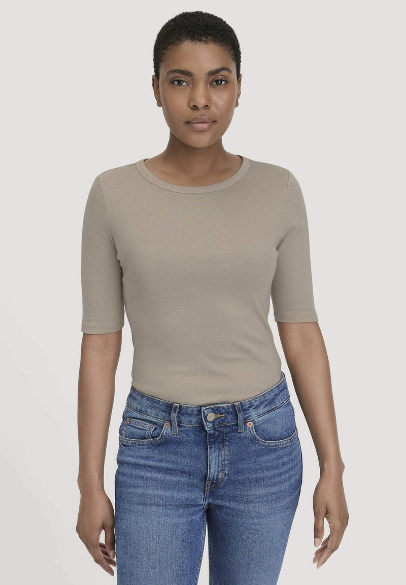Beige T-shirt met korte mouwen en een ronde halslijn, aansluitend design, zachte textuur, gecombineerd met blauwe high-waisted jeans met traditionele zakken.