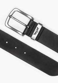 Ceinture en cuir noir avec une boucle métallique argentée, trois trous pour l'ajustement et une texture lisse. Présente un détail de logo sur le métal.