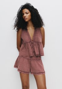 Rosenfarbene, leichte Zweiteiliges Loungewear-Set besteht aus einem ärmellosen Top mit Wellenkante und Kordelzug, kombiniert mit Shorts mit gewelltem Saum.
