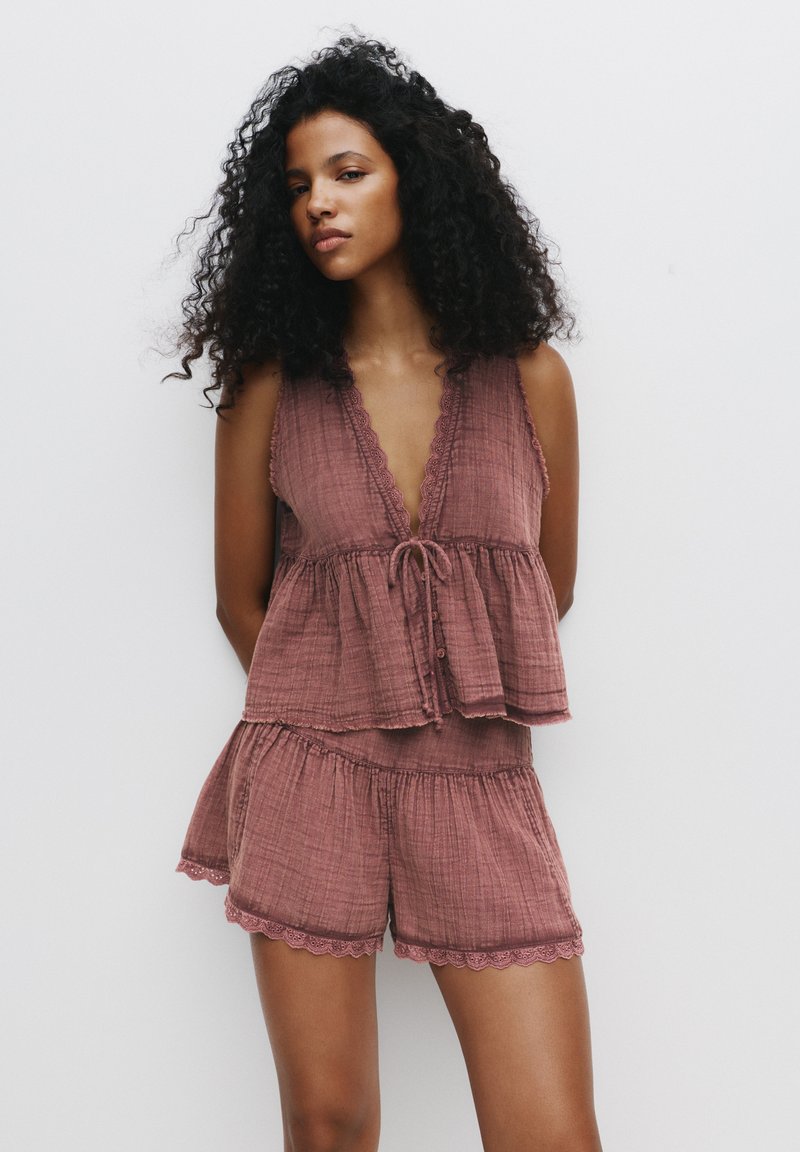 Rosenfarbene, leichte Zweiteiliges Loungewear-Set besteht aus einem ärmellosen Top mit Wellenkante und Kordelzug, kombiniert mit Shorts mit gewelltem Saum.