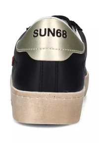 Basket noire avec accent doré au talon, présentant une semelle beige texturée. Logo "SUN68" imprimé en noir sur la section dorée.