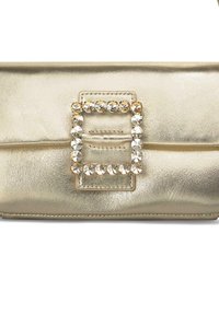 Bolso de mano metálico dorado con un hebilla rectangular acentuada con strass en el centro y una textura suave.
