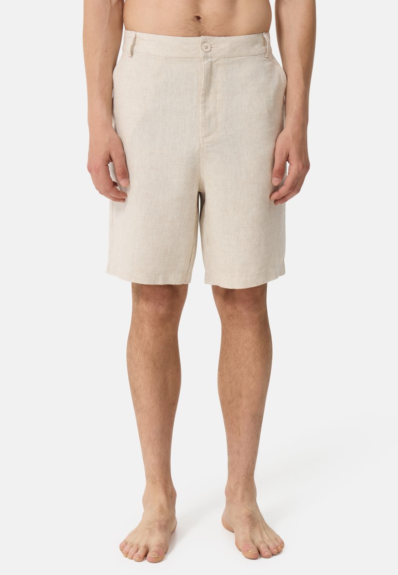 Shorts en lin beiges avec un devant plat, deux poches latérales et une fermeture à bouton unique. Coupure droite avec une texture lisse. Sans motifs ni accents.
