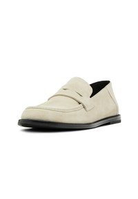 Beige suede loafers with a stitched toe cap, a raised strap, and a black rubber sole, featuring a smooth texture and minimal design.