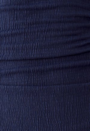 Marineblauer Stoff mit einer gerafften, strukturierten Oberfläche, die kleine vertikale Rillen aufweist und einen Rüscheffekt erzeugt.