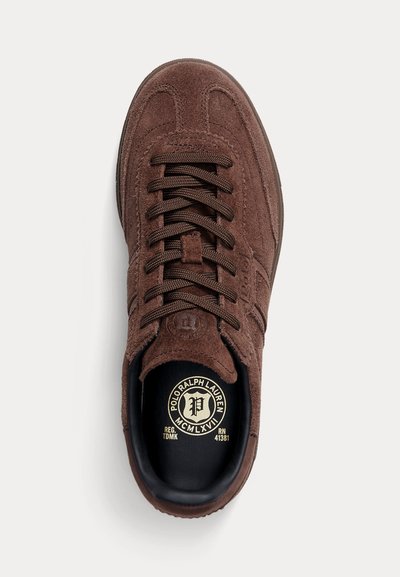 Brązowy zamszowy sneaker z ciemnobrązowymi sznurowadłami, okrągłym noskiem i logo Polo Ralph Lauren na wkładce.