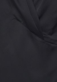 Schwarzer Stoff mit einem drapierten Design, weicher Textur und subtiler Hochglanz-Oberfläche. Das Material ist glatt und erzeugt elegante Falten und Konturen.
