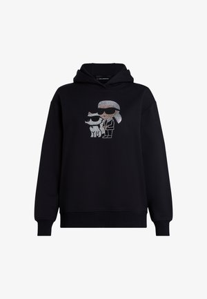 Fekete kapucnis pulóver, melyen egy napszemüveges karakter és egy kutya strasszköves grafikája látható, mindkettő vastag körvonalakkal. Puha, texturált anyag.