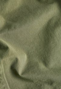 Materiały w kolorze oliwkowym o gładkiej fakturze i ukośnym splocie, widocznymi naturalnymi zagnieceniami i delikatnym połyskiem. Odpowiednie na odzież lub akcesoria.