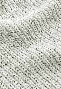 Texturerad tyg i vitt och grått, med ett kraftigt stickat mönster med öglor och trådar. Mjukt och varmt utseende med synliga fiberdetaljer.