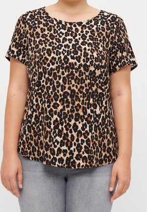 Korte mouwen blouse met luipaardprint gedragen door een persoon, gecombineerd met lichtgrijze jeans, kort afgeknipt bij de hals en heupen.