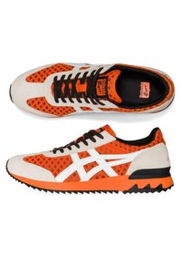Chaussures de sport orange et blanches en mesh avec lacets noirs, accents en daim, semelle rembourrée et semelle en caoutchouc texturée. Présentent le logo Onitsuka Tiger.