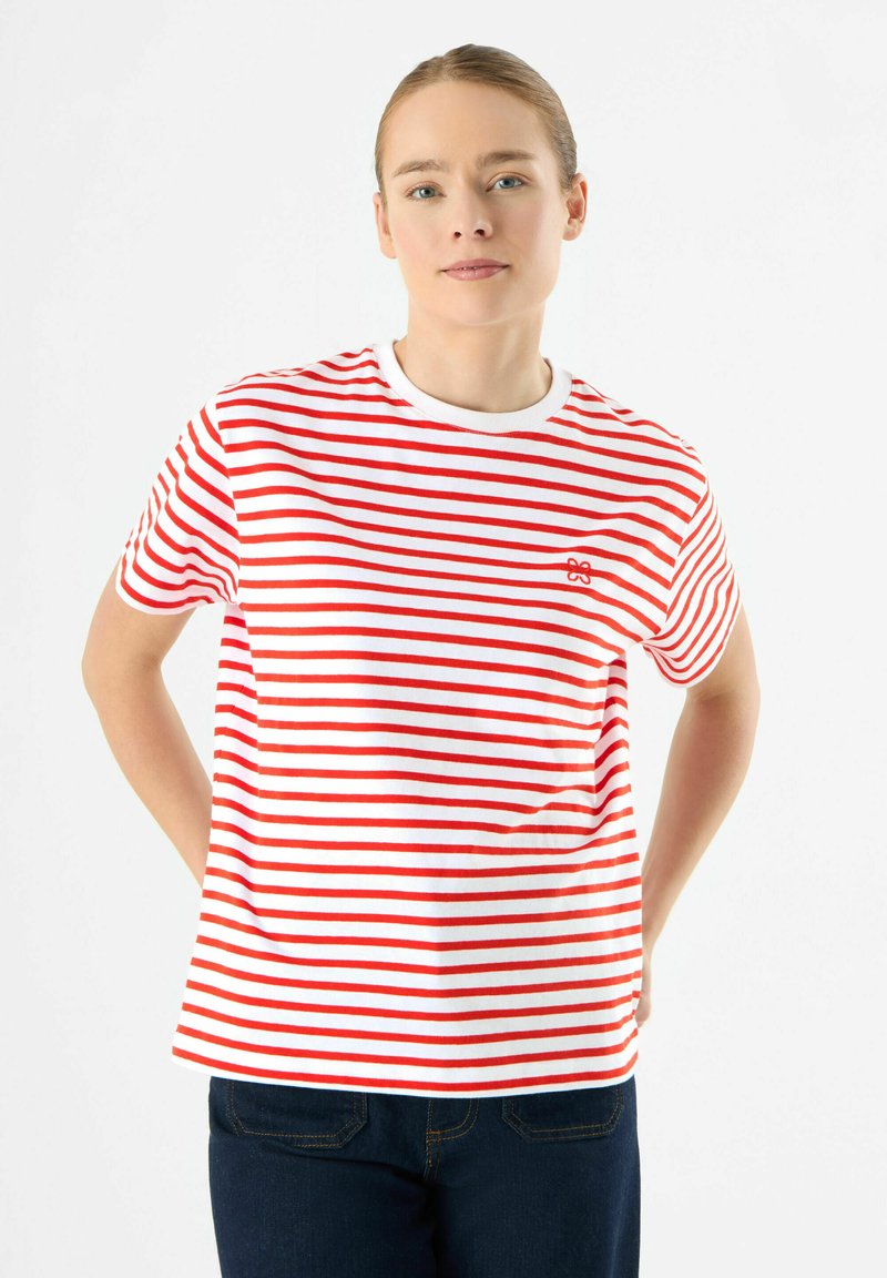 Witte T-shirt met rode horizontale strepen, ronde halslijn en korte mouwen. Heeft een klein rood logo op de linkerborst. Casual pasvorm.