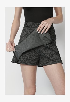 Fekete és szürke leopárdmintás nadrág, texturált anyagból, széles derékkal és laza fazonnal. Egy illeszkedő darabot tartanak.