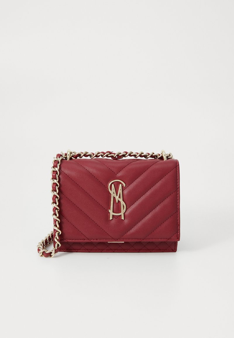 Red quilted handbag made of textured material with a gold chain strap and logo detail. Features chevron pattern on the front.