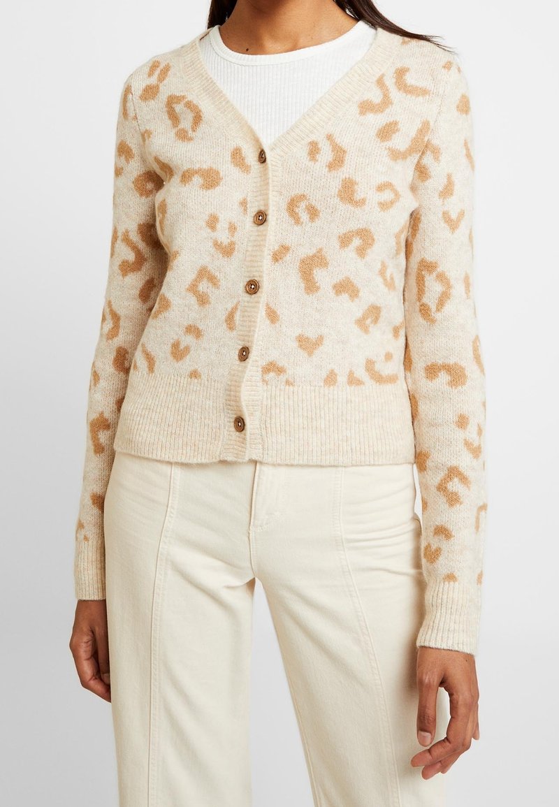 Cárdigan beige con estampado de leopardo marrón claro, diseño de escote en V, cierre de botones, puños y dobladillo acanalados, hecho de una tela suave y con textura.