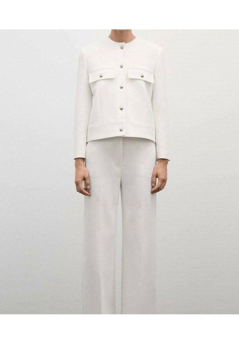 Veste blanche courte avec deux poches poitrine et boutons-pression métalliques, associée à un pantalon blanc à jambes larges, tous deux en texture lisse.