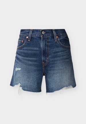 Shorts en denim bleu avec bords effilochés et patchs usés sur un fond clair uni, vue de face.