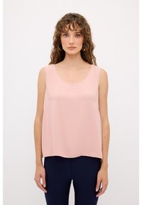 Top senza maniche di colore rosa pallido in tessuto morbido e liscio, con scollatura rotonda e vestibilità rilassata, abbinato a pantaloni blu scuro.
