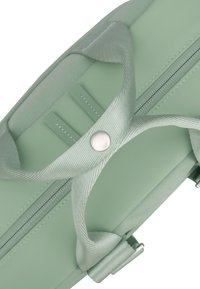 Zöld kiegészítő táska sima, matt felülettel, dupla cipzárral, texturált pántokkal és ezüst szorítóval a fogantyún.