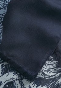 Tissu bleu marine à texture lisse, présentant un motif délicat contrasté en dessous, fini avec un ourlet.
