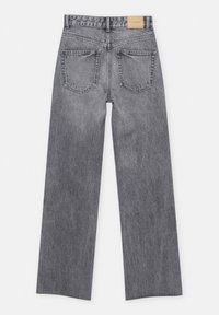 Jean droit en denim gris avec deux poches arrière et une étiquette en cuir beige sur la ceinture.