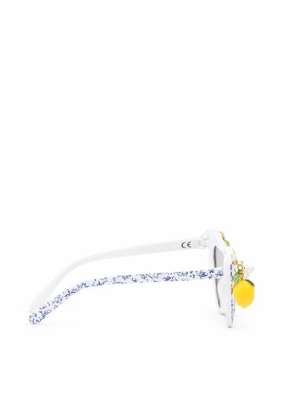 Weiße Sonnenbrille mit blauen, floral gemusterten Bügeln und einem kleinen, dekorativen gelben Zitronenanhänger an der Seite des Gestells.