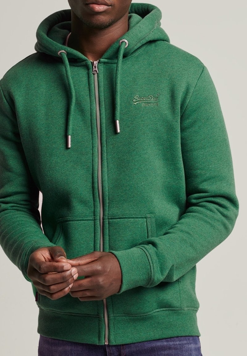 Felpa verde con zip, dotata di cordini, tasche a marsupio e un accento con logo. Realizzata in morbido tessuto texturizzato, presenta polsini e orlo a costine.
