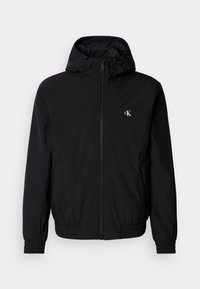 Μαύρο ελαφρύ μπουφάν με κουκούλα, ελαστικά μανσέτες και τελείωμα, πλήρες φερμουάρ μπροστά και λογότυπο στο αριστερό στήθος. Λείο, ματ υλικό.