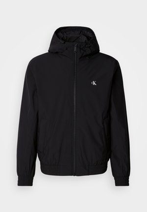 Black lightweight jacket with a hood, elastic cuffs and hem, full front zipper, and logo on the left chest. Smooth, matte texture.