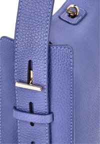 Sac à main en cuir bleu clair avec une finition texturée, présentant une forme structurée, des accessoires en or et une sangle cousue avec un détail de boucle.