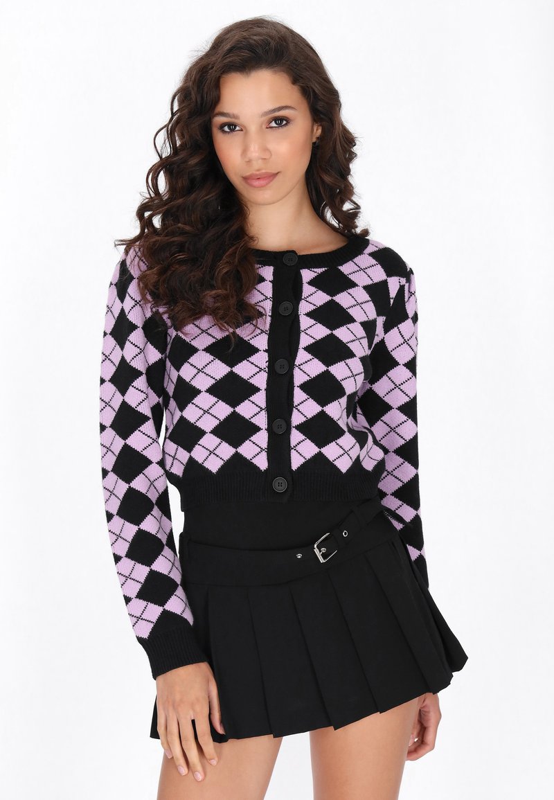 Čierny a levanduľový argyle vzorovaný skrátený kardigán so šiestimi veľkými gombíkmi, spárovaný s čiernou plisovanou sukňou s akcentom opasku.