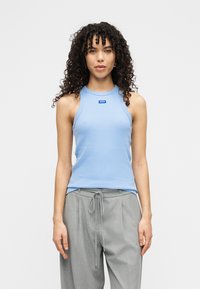 Ανοιχτό μπλε ριγωτό φανελάκι με στρογγυλή λαιμόκοψη, με ετικέτα λογότυπου στο στήθος· σετ με γκρι, φαρδιά παντελόνια με κορδόνι στη μέση.