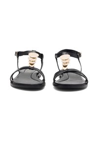 Czarne płaskie sandały z paskiem w kształcie litery T, ozdobione złotym dyskiem i gładką skórzaną fakturą na wyprofilowanej wkładce.