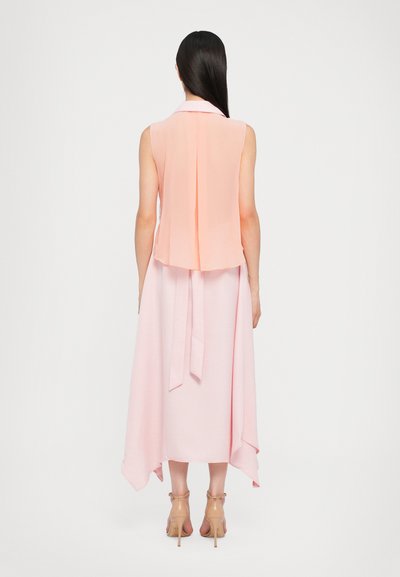 Abito senza maniche in rosa chiaro, con un retro a strati e una cintura in vita. Presenta un tessuto morbido e una silhouette fluida che scivola elegantemente.