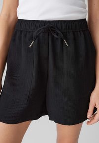 Černé žebrované šortky s elastickým pasem a tkaničkou, obsahující dvě přední kapsy a pohodlný střih.