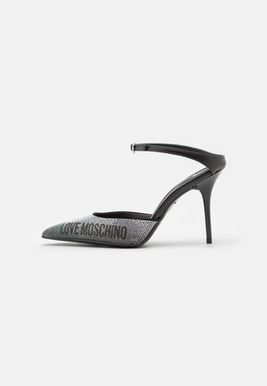 Czarny but na wysokim obcasie typu slingback z ostrym noskiem pokryty małymi srebrnymi cyrkoniami na białym tle.
