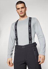 Pantalones de nieve negros con tirantes ajustables negros, con un diseño elegante y bolsillos con cremallera laterales, combinados con una camiseta de manga larga gris claro.