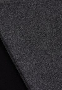 Tissu gris foncé, à texture douce avec un aspect légèrement duveteux, replié sur un matériau noir lisse. Met l'accent sur la qualité du textile et le contraste des couleurs.