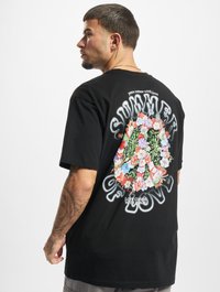 Sort T-shirt med korte ærmer, der har et blomstermotiv og teksten "SUMMER OF LOVE" på tilbage. Blødt stof, afslappet pasform.