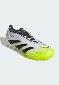 White and neon yellow Adidas Predator football boot with black stripes, laces, and cleats, detailed texture, and "Hybridtouch" label.