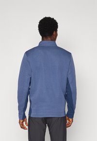 Pullover blu a maniche lunghe con motivi a coste testurizzati, dotato di un collo alto e di un pannello di colore uniforme sulle maniche.