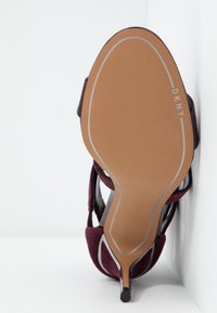 Bordová lodička na vysokém podpatku s hladkým koženým svrškem a texturovaným semišovým povrchem. Disponuje úzkým jehlovým podpatkem a lehce polstrovanou podrážkou.