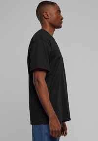 Svart t-shirt med korta ärmar, tillverkad av bomull, med en klassisk rund halsringning och en avslappnad passform. Enkel och solid design.