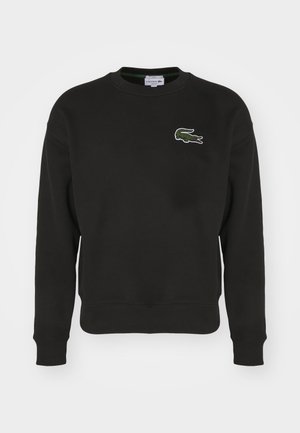 Zwarte sweater gemaakt van katoen met een ronde halslijn. Heeft een klein groen Lacoste krokodillenlogo op de linkerkant van de borst. Ribgebreide boorden en zoom.